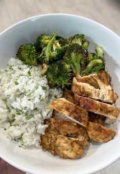 a white bowl filled with rice, meat and broccoli