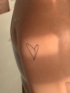 a woman with a small heart tattoo on her left side ribcading the chest