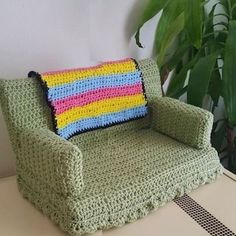 a crocheted couch sitting on top of a table next to a potted plant