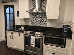 a kitchen with white cabinets and black counter tops, stainless steel stove top oven and dishwasher