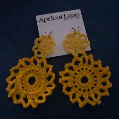 pair of yellow crochet earrings on black surface with white tag attached to it