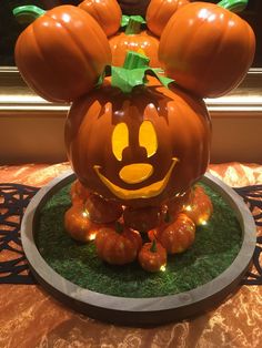 a mickey mouse pumpkin sitting on top of a green plate with some lights around it