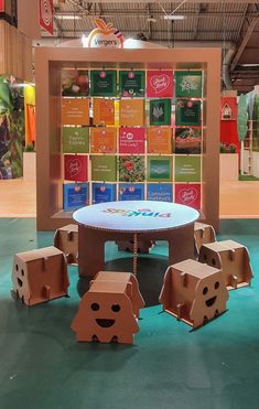 a table and chairs made out of cardboard boxes on display in a building with an advertisement behind it