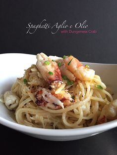 a white bowl filled with pasta and shrimp on top of a black tablecloth covered table