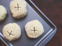 four uncooked doughnuts with crosses on them sitting in a baking pan