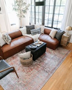 a living room with brown leather couches and pillows on top of a large rug