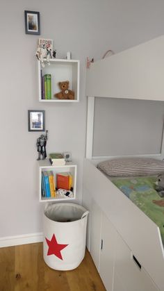 a bedroom with a bed, bookshelf and toy bin in the corner on the floor