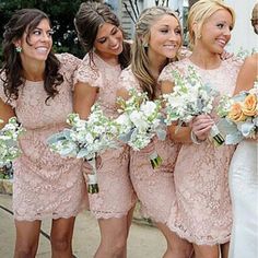 a group of women standing next to each other in front of a white building holding bouquets