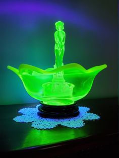 a green glass bowl sitting on top of a table next to a blue doily