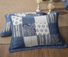 two blue and white pillows sitting on top of a wooden floor next to vases