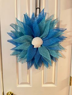 a door with a blue mesh wreath hanging on it's side and a sea shell in the center