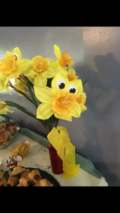 a vase filled with yellow flowers sitting on top of a table covered in pastries