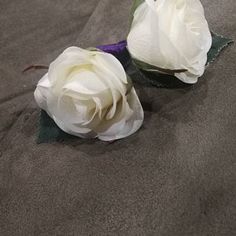 two white roses sitting on top of a bed