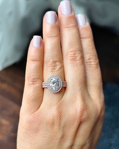 a woman's hand with a diamond ring on her finger and the other hand holding an engagement ring