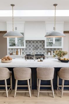 an image of a kitchen setting with white cabinets and gray counter tops, hanging lights over the island