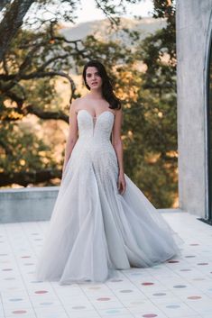 a woman in a wedding dress standing on a tiled floor with trees in the background