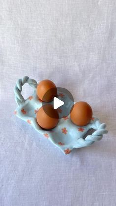 three brown eggs in a blue tray on a white tablecloth