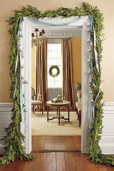 an archway decorated with greenery and blue ribbon is open to the dining room area