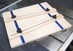 three pieces of wood with blue tape on them sitting on a metal workbench