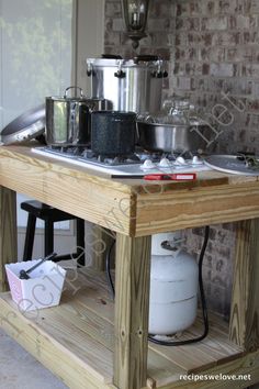 a stove top oven sitting on top of a wooden table next to a brick wall