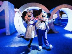 mickey and minnie mouse posing for a photo in front of the numbers 10 at disneyland world