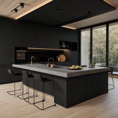 a modern kitchen with black cabinets and counter tops, along with bar stools that match the hardwood flooring