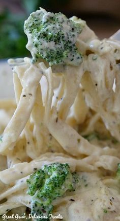 a fork full of pasta with broccoli and cheese on it is being lifted from the plate