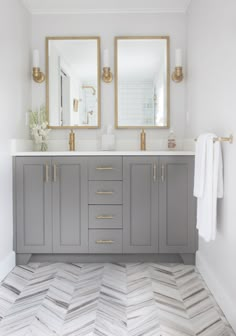 a bathroom with two sinks and mirrors on top of the cabinets, along with herringbone tile flooring