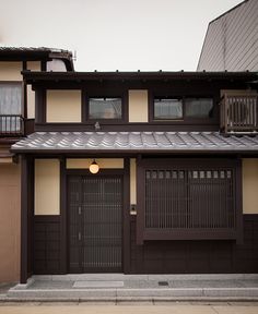 a brown and tan house with a black door on the side walk in front of it