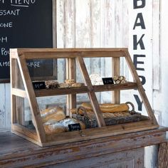 a display case with bread and pastries in front of a chalkboard sign that says bakery