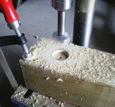 a drill is being used to make a hole in a piece of wood