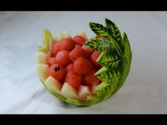 a watermelon fruit bowl with leaves and berries in it