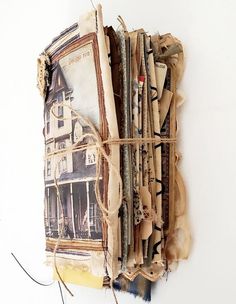 an old book with torn pages and string attached to the cover is sitting on a white surface