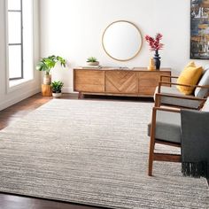 a living room with white walls and wooden furniture, including a gray rug on the floor