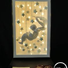 a lit up window with stars hanging from it's sides and a woman in the middle