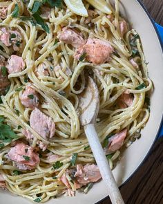 a plate of pasta with salmon and parsley on the side next to a spoon