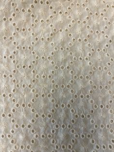 an upholstered fabric with white flowers and circles on it's surface, as well as the background