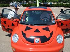 an orange car with a jack - o'- lantern face painted on the front