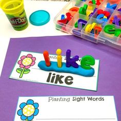 some sort of sight words that are on a purple table with plastic containers and flowers