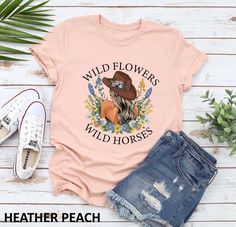 "wild flowers wild horses shirt, western country, western shirt, cowgirl gift, country girl gift, horse lover, western shirt, shirt for women, concert top, nashville shirt, matching family, country concert, wild horses, country music, gift for her, wild flowers, shirts for women, toddler girl, wild horses shirt, cute woman shirt, country concert top, rodeo shirt, western gift, country shirt, lainey wilson, wild flower shirt, cowgirl shirt, country music shirt, cowboy shirt, country shirt, western shirt, girls shirt, country girl shirt, wildflowers, horse lover gift, infant graphic shirt, wildflower shirt, newborn bodysuit, western, horsemanship shirt" -------DESIGN COLORS------- Black text/design will be printed on Light color shirts White text/design will be printed on Dark color shirts - Summer Graphic Print T-shirt For Country Events, Summer Graphic Print Tops For Country Events, Graphic Print Tops For Country Events In Summer, Graphic Print Tops For Summer Country Events, Spring Country Style T-shirt With Graphic Print, Country Style Graphic Print T-shirt For Spring, Graphic Print T-shirt For Summer Country Events, Country Style T-shirt For Spring Events, Spring Country Style T-shirt For Country Events