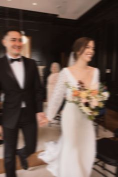 a bride and groom are walking through the room together in their tuxedo attire