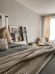 a large bed sitting next to a window covered in pillows and blankets on top of it