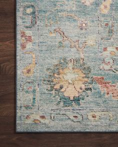 a blue area rug with an ornate design on the top and bottom, in front of a wooden floor