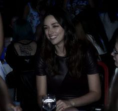 a woman sitting at a table with a drink in front of her and people behind her