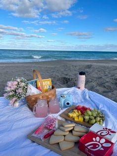 a picnic on the beach with food and drinks laid out in front of the ocean