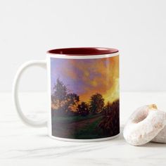 a painting on a coffee mug next to a donut