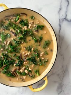 a pot filled with broccoli and mushrooms on top of a marble counter