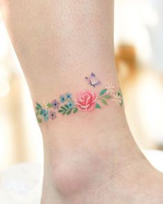 a woman's foot with a flower and butterfly tattoo on the side of her ankle