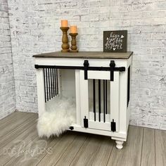 a white dog crate sitting on top of a wooden floor next to a brick wall