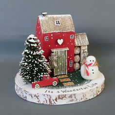 a christmas scene with a red house, snowman and tree on a white base